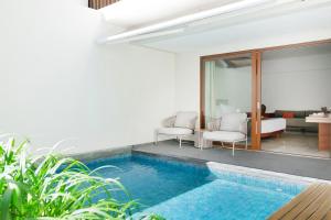 a villa with a swimming pool and a living room at The Magani Hotel and Spa in Legian