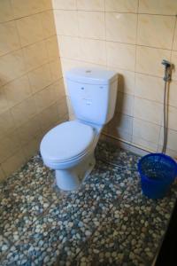 a white toilet in a bathroom with a blue bucket at Pondok Balian in Selemadeg