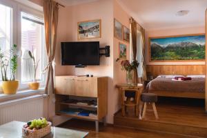 1 dormitorio con 1 cama y TV en la pared en Vila Katarína 151, en Tatranská Lomnica