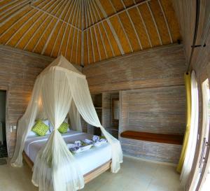 a bedroom with a bed with a mosquito net at Mesari Hut Lembongan in Nusa Lembongan