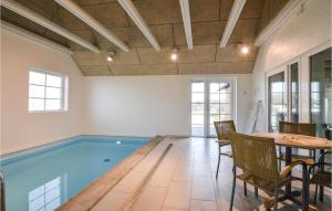 Nørre LyngvigにあるAwesome Home In Ringkbing With 6 Bedrooms, Wifi And Indoor Swimming Poolのテーブルと椅子付きの客室内のスイミングプールを利用できます。