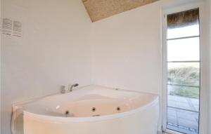 eine weiße Badewanne in einem Badezimmer mit Fenster in der Unterkunft 6 Bedroom Awesome Home In Ringkøbing in Nørre Lyngvig + 33 Fotos