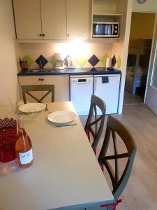 una cocina con mesa con 2 sillas y una botella de vino en Studio 4 personnes, climatisé, rez de jardin, en Saint-Raphaël