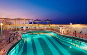 a swimming pool at night with tables and chairs at Avenue Hotel Dubai in Dubai