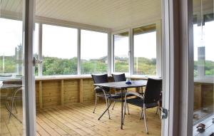 スナーヴィグにあるLovely Home In Ringkbing With Saunaの窓、テーブル、椅子が備わるポーチ