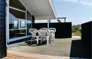 un patio con sillas blancas y una mesa en una casa en Pet Friendly Home In Ringkbing With House A Panoramic View, en Søndervig