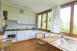 eine Küche mit weißen Schränken sowie einem Tisch und Stühlen in der Unterkunft Edelweiss Haus Collina in Flims