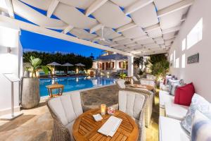 a patio with a table and chairs next to a pool at Stelia Mare Boutique Hotel in Naousa