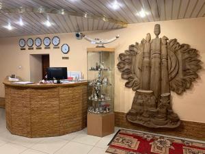a lobby with a counter with a large wooden statue at Hotel Timpton in Neryungri