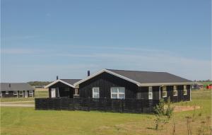 a black house with a fence in a field at Four-Bedroom Holiday Home In Lokken in Løkken