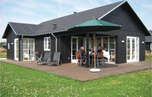 una casa negra con gente sentada en una mesa en una cubierta en 3 Bedroom Nice Home In Nysted, en Nysted