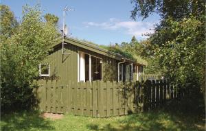 a small green house with a wooden fence at Beautiful Home In Pandrup With 3 Bedrooms, Sauna And Wifi in Rødhus