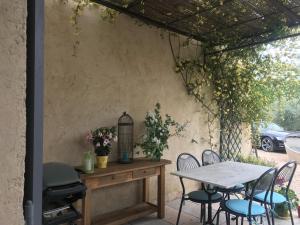 a patio with a table and chairs and a grill at La Petite Garrigue in Mérindol