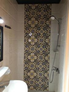 a bathroom with a shower and a tile wall at Tulip Hotel in Cairo
