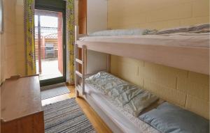 EgernsundにあるAwesome Home In Egernsund With 3 Bedroomsの二段ベッド2台と窓が備わる客室です。