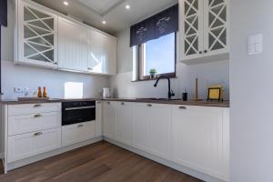 a white kitchen with white cabinets and a window at Amare Apartments A1 in Mosty