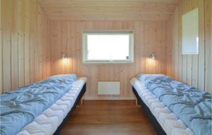 two beds in a room with a window at Nice Home In Idestrup With 4 Bedrooms, Sauna And Wifi in Marielyst