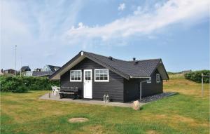 a black house with a white door in a yard at Stunning Home In Ringkbing With Kitchen in Søndervig