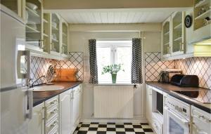 Una cocina con gabinetes blancos y piso a cuadros. en Holiday Home Fyrmarken Iv, en Nørre Lyngvig