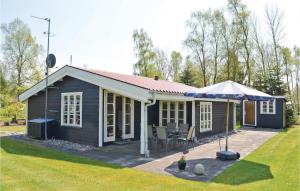 a small black house with a patio and an umbrella at Holiday Home Bøtø Ringvej in Marielyst