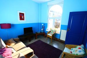 ein blaues Wohnzimmer mit einem Sofa und einem TV in der Unterkunft Gîte de la Conciergerie du Cheval Blanc in Luttre