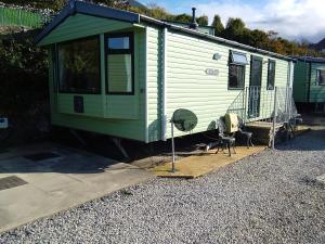 巴茅思Hendre Coed Isaf static caravan Barmouth的绿色拖车,配有椅子和风扇