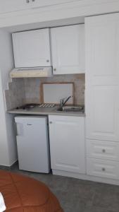 eine Küche mit weißen Schränken und einem Waschbecken in der Unterkunft Heliotropio Studios & Apartments in Pollonia