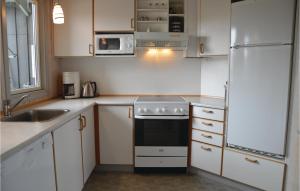 a kitchen with white cabinets and a sink and a refrigerator at Holiday Home Klægdalen in Halkær