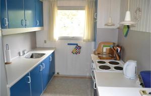 a small kitchen with blue cabinets and a sink at Holiday Home Uranusvej in Ålbæk