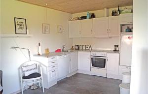 una cocina con armarios blancos y una silla. en Stunning Apartment In Middelfart With Kitchen en Middelfart