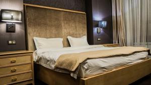a bedroom with a large bed with a wooden headboard at JELSOMINOHotel in Astana