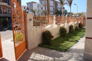 Al Raya Apartments في الإسكندرية: بوابة برتقالية في سياج به نباتات
