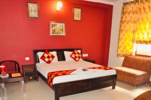 a bedroom with red walls and a bed and a chair at Tuk Tuk Backpackers Jaipur in Jaipur