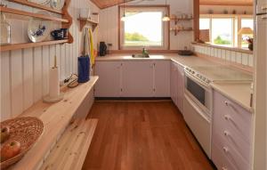 cocina con armarios blancos y suelo de madera en Cozy Home In Krus With House Sea View, en Kruså