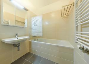 Residence Port Karolina في براغ: حمام أبيض مع حوض وحوض استحمام