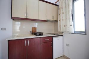 cocina con armarios de madera, fregadero y ventana en Vila Leo, en Ksamil