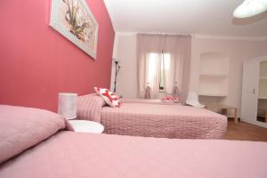 a bedroom with two beds and a pink wall at Casetta Margret in Boiano