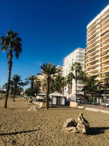 a sandy beach with palm trees and a building at New Luxury Premium in Málaga