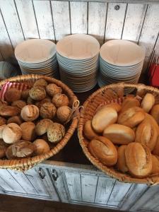dois cestos cheios de diferentes tipos de pão e pilhas de pratos em Der LeuchtTurm-Gastro GmbH em Geierswalde