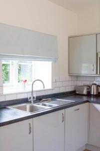 uma cozinha branca com um lavatório e uma janela em Cromhall Farm em Chippenham