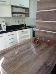 a kitchen with white cabinets and a wooden floor at Aptos Farroupilha in Farroupilha