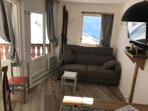 a living room with a couch and two windows at Le Necou - Reberty 2000 in Les Menuires