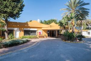 ミハスにあるMiraflores Apartmentのヤシの木と私道のある黄色い建物