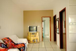 a living room with a couch and a television at Resid.l Canto do Encanto in Garopaba
