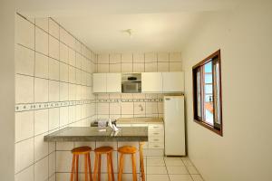 a kitchen with a sink and two bar stools at Resid.l Canto do Encanto in Garopaba +8 photos