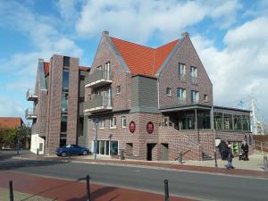 un grand bâtiment en briques sur le côté d'une rue dans l'établissement Mingers Hotel, à Neuharlingersiel