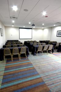 une salle de conférence avec des tables, des chaises et un écran dans l'établissement Holiday Inn Houma, an IHG Hotel, à Houma