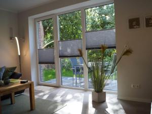 a living room with large windows and a plant at Zeitlos Langeoog in Langeoog