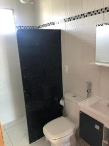 uma casa de banho com WC e uma porta preta em Porto Cavalinho apartamento 10 em Porto de Galinhas