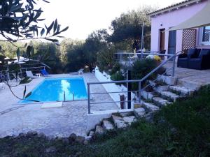 a swimming pool with stairs leading to a house at Holiday Home Matthäus am Corfutrail, Ferienoase im Olivenhain 3 km zum Meer in Giannádes